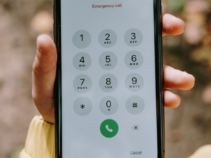 A hand holding a cell phone prepped to make an emergency dental appointment