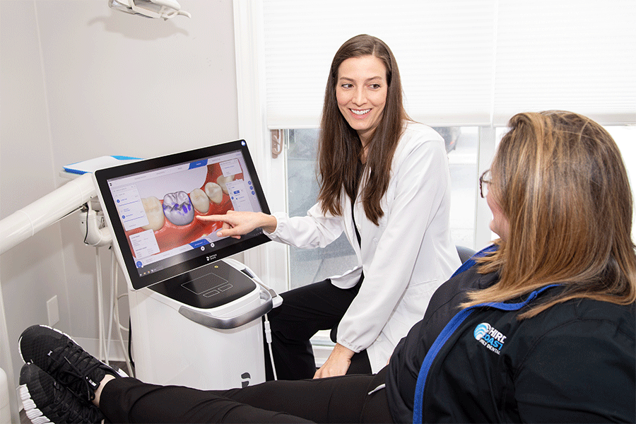 Dentist Dr. Andrea Emmerich pointing to a computer to explain a dental procedure to a patient.