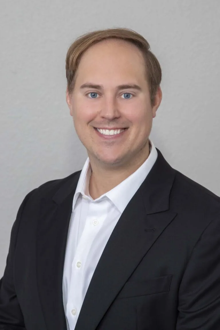 The image shows Dr. Nick Dwan, a dental professional wearing a black V-neck scrub top with the text "Nicholas Dwan DDS." The face is blurred in the photograph.