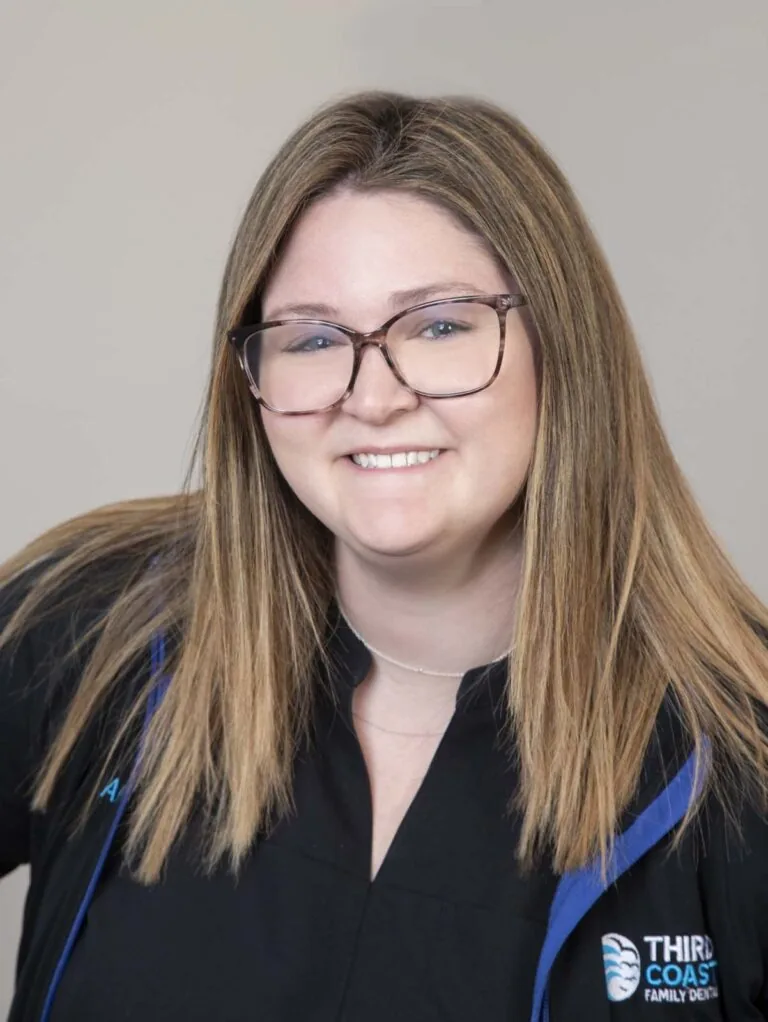 The image shows Abigail (Abby) Reinhold, a person wearing a black uniform with blue accents and the text "THIRD COAST FAMILY DENTAL" on the chest area.