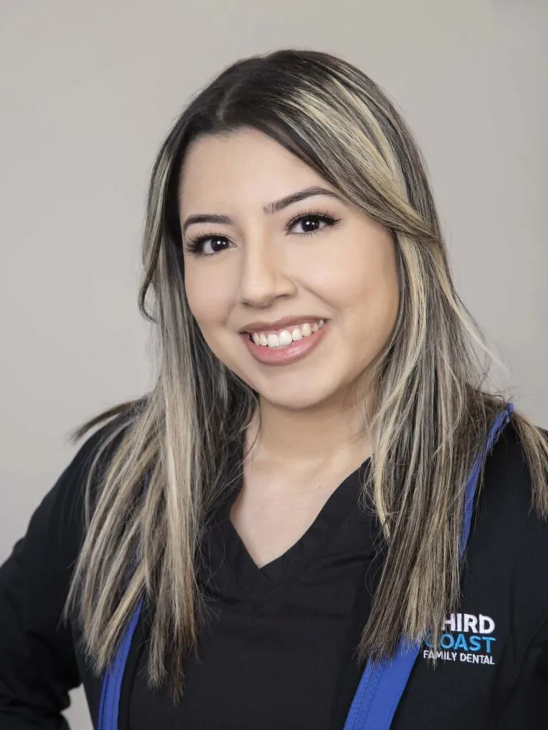 The image shows a woman smiling, wearing a black top and a black jacket with blue accents, labeled "THIRD COAST FAMILY DENTAL." The individual's name is Selina.